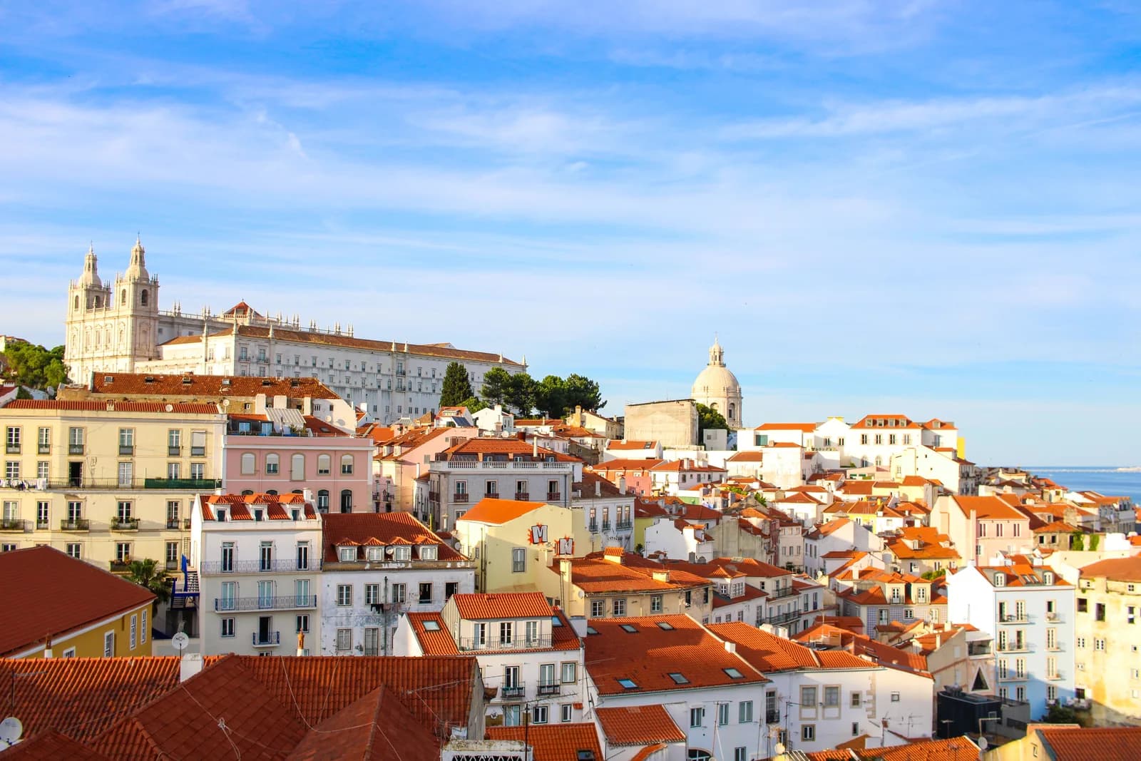 Telhados e fachadas claras do bairro de Alfama vistos de um miradouro em Lisboa